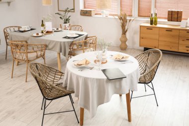 Masaları ve çekmeceleri olan hafif bir restoranın içinde.