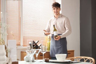 Restoranda bir şişe şarap gösteren erkek garson.