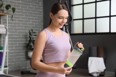 Spor salonunda bir şişe suyu olan genç bir kadın.
