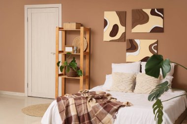 Tabloları, raf ünitesi ve kapısı olan şık bir yatak odası.