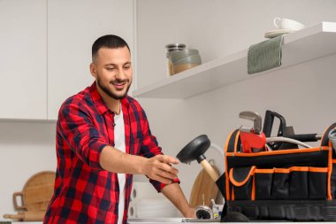 Alet çantalı erkek tesisatçı mutfağı temizliyor.