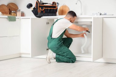 Erkek tesisatçı mutfakta lavabo borusunu tamir ediyor.