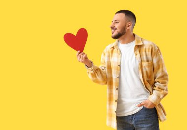 Sarı arka planda kırmızı kalpli genç adam.