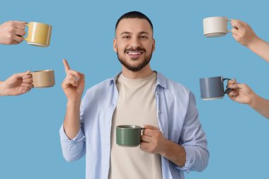 Mavi arka planda seramik bardaklı genç adam ve eller