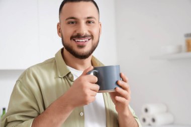 Mutfakta seramik bardaklı genç adam, yakın plan.