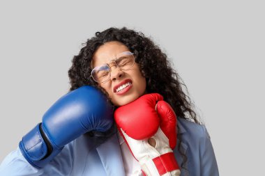 Genç Afro-Amerikalı iş kadını yüzüne boks eldiveniyle vuruluyor, yakın plan. Nakavt konsepti