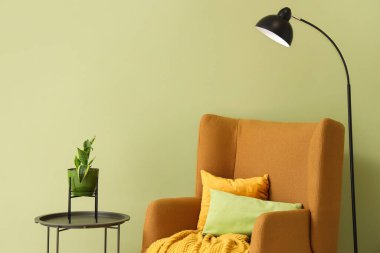 Koltuklu siyah lamba ve yeşil duvarın yanındaki masa.