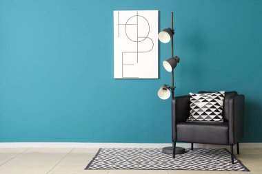 Koltuklu siyah lamba ve mavi duvarlı afiş.