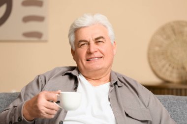 Oturma odasında bir fincan sıcak kahveyle yakışıklı son sınıf öğrencisi.