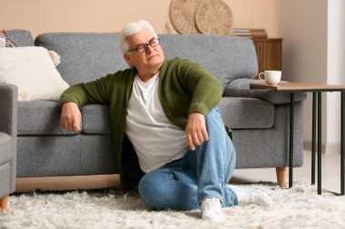 Yakışıklı son sınıf öğrencisi oturma odasında halıda oturuyor.