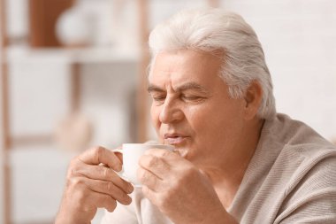 Oturma odasında bir fincan sıcak kahveyle yakışıklı son sınıf öğrencisi.