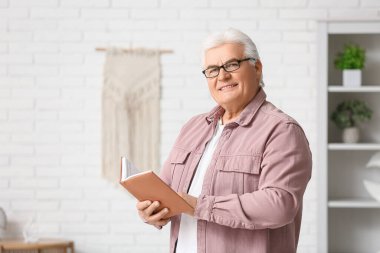 Oturma odasında kitabı olan yakışıklı bir son sınıf öğrencisi.