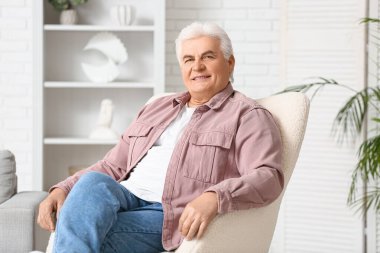 Evdeki koltukta oturan yakışıklı kıdemli adam.