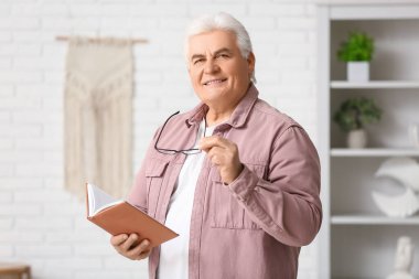 Oturma odasında kitabı olan yakışıklı bir son sınıf öğrencisi.