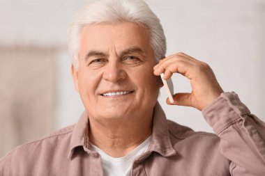 Yakışıklı son sınıf öğrencisi evde cep telefonuyla konuşuyor, yakın plan.