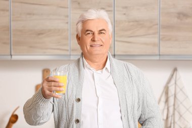 Mutfakta bir bardak taze meyve suyu olan yakışıklı bir son sınıf öğrencisi.