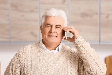 Yakışıklı son sınıf öğrencisi mutfakta cep telefonuyla konuşuyor.