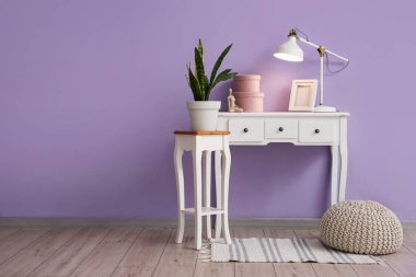 Beyaz masa tarzı masa lambası, dekorasyon ve çiçek, leylak duvarın yanında.