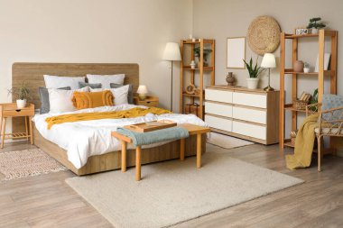 Şık yatak odasının içinde raf üniteleri ve rahat yatağın yanında standart lamba var.