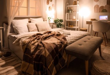 Şık, rahat yatak odasının içinde iş yerinde dizüstü bilgisayar ve akşam lambaları var.