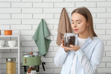 Mutfakta kahve kavanozu olan genç ve güzel bir kadın.