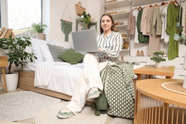 Yatak odasında dizüstü bilgisayar kullanan genç bir kadın.