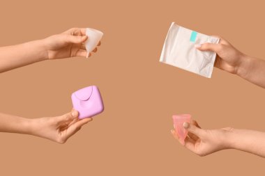 Regl bardakları, ped ve tampon kutuları bej arka planda olan kadın elleri.