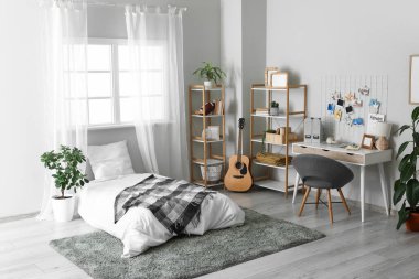 Yatak, işyeri ve raf üniteleri olan bir gencin odasının içinde.