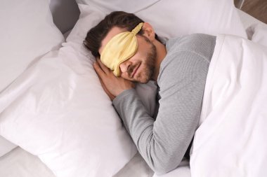 Uyku maskeli yakışıklı genç adam evde uyuyor.