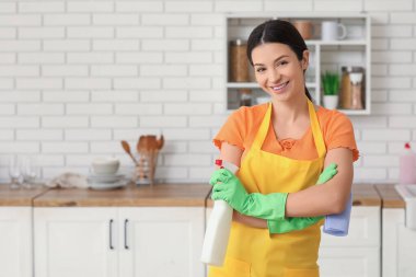 Mutfakta temizlik spreyi ve bezi olan genç bir kadın.