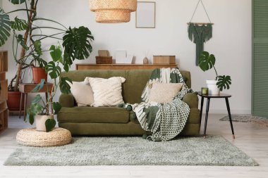 Oturma odasının içinde rahat bir kanepe ve Monstera bitkileri var.