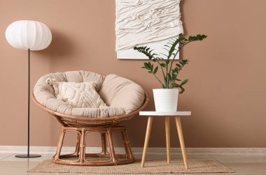 Oda içinde lamba, rahat koltuk ve kahverengi duvarın yanındaki bitki örtüsü.