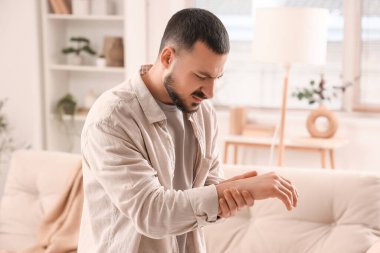 Evinde bileğinde ağrı olan genç bir adam.