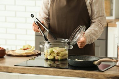 Kadın mutfaktaki fırında pişirme kabından lahana sarması alıyor, yakın plan.