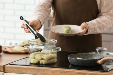 Doldurulmuş lahana rulolarını mutfaktaki tabağa koyan kadın.