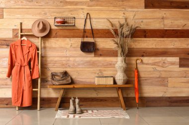 Çantalı bank, vazodaki otlar ve koridordaki merdivende asılı duran palto.