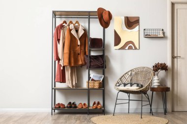 Hasır koltuk, kahve masası, koridorun iç tarafındaki elbise ve aksesuarlarla dolu raflar.