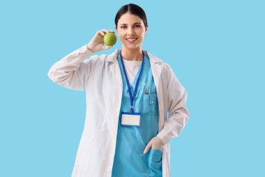 Mavi arka planda elmalı kadın dişçi.