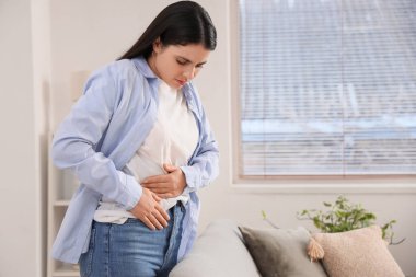 Evde karın ağrısı çeken genç bir kadın.