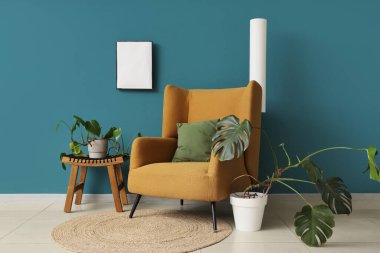 Koltuk ve canavar çiçekleri mavi duvarın yanında.