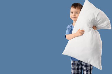 Mavi arka planda yastığı olan şirin bir çocuk.