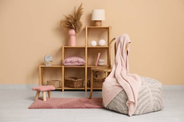 Dışkı, raf ünitesi ve oturma odasındaki bej duvarın yanında farklı mercan dekorlarıyla dolmuş.