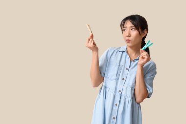 Bej arka planda mandalları olan düşünceli Asyalı genç bir kadın.