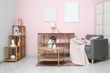 Masası, koltuğu ve rafları pembe duvarın yanında olan aydınlık oturma odasının içinde.