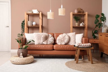 Oturma odasının iç tarafında rahat bir kanepe, tabure ve saksı.