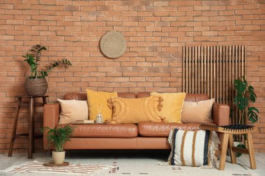 Rahat bir kanepe, minderli bir tabure ve oturma odasının iç tarafında bitkiler.