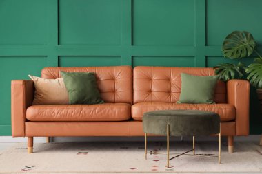 Oturma odasının içinde kahverengi kanepe ve puf.