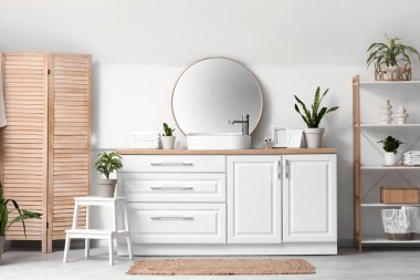 Lavabosu, raf ünitesi ve yeşil bitkileri olan hafif banyonun içi.