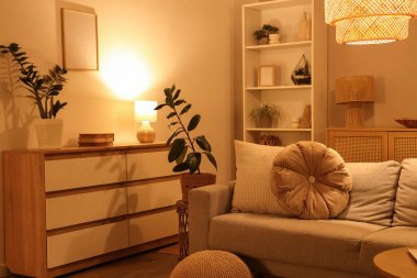 Konforlu kanepe, çekmeceler ve oturma odasının içinde parlayan lambalar.