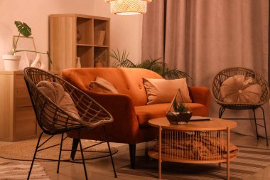 Akşamları kırmızı kanepe, sehpa, koltuklar ve parlayan lambayla modern oturma odasının içinde.